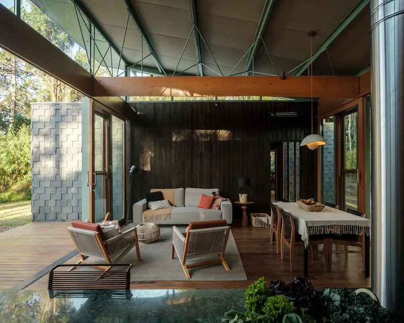 Covered timber deck with exposed concrete ceiling and steel tension rods sheltering the living area