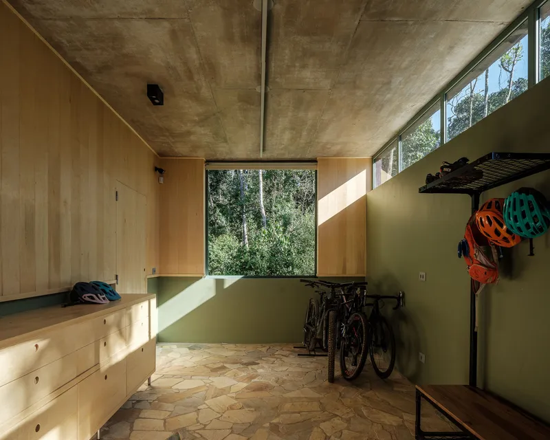 Utility room with plywood walls, exposed concrete ceiling and clerestory window framing trees outside