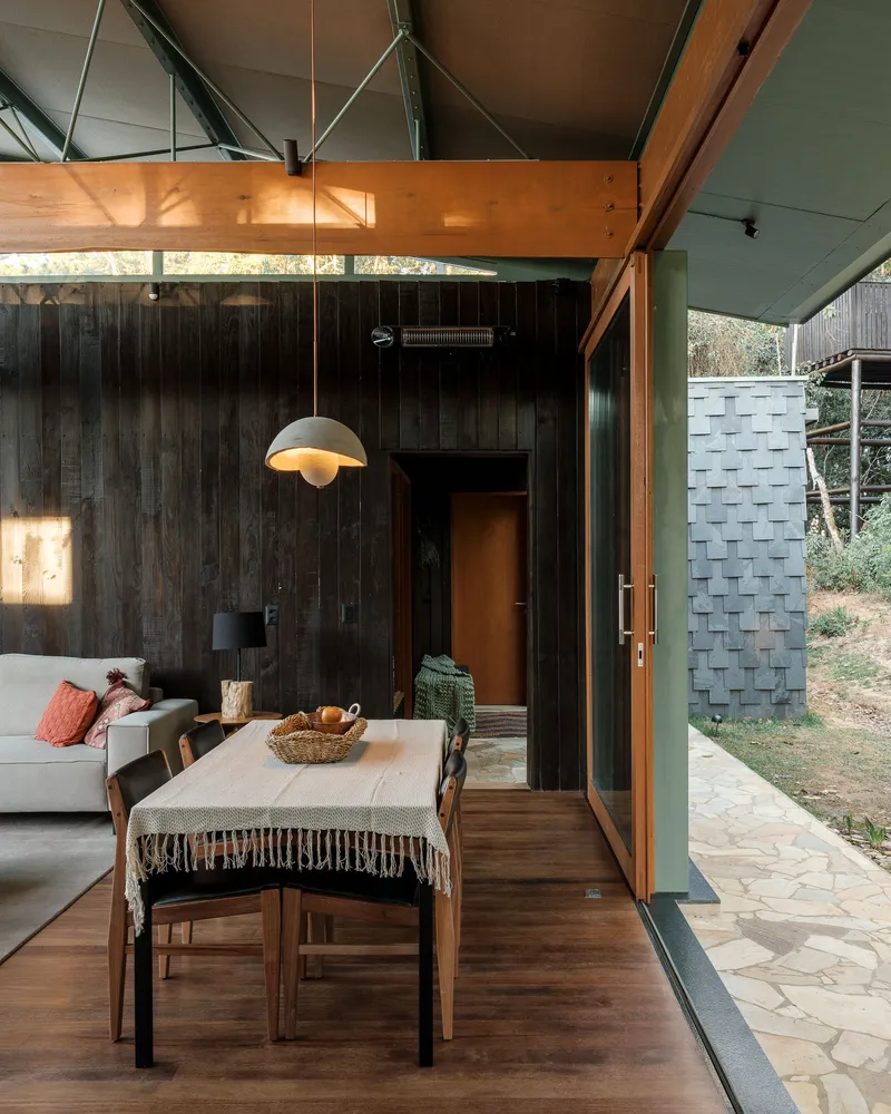 Dining area with charred timber wall and pendant light beside a glazed door opening to the courtyard