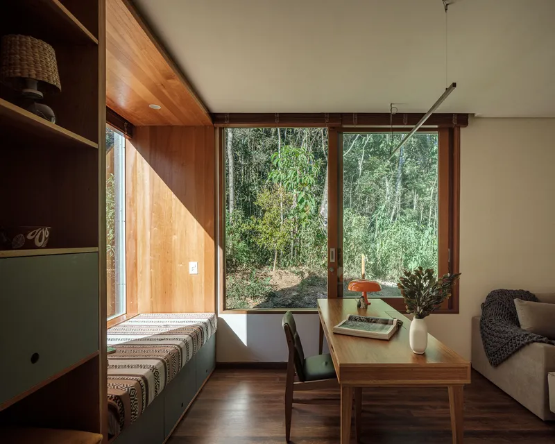 Interior living space with corner windows overlooking bamboo grove and built-in seating along timber wall