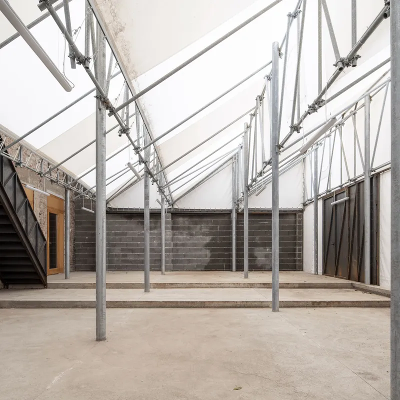 Interior courtyard with galvanized steel structural frame supporting a translucent roof over concrete block walls