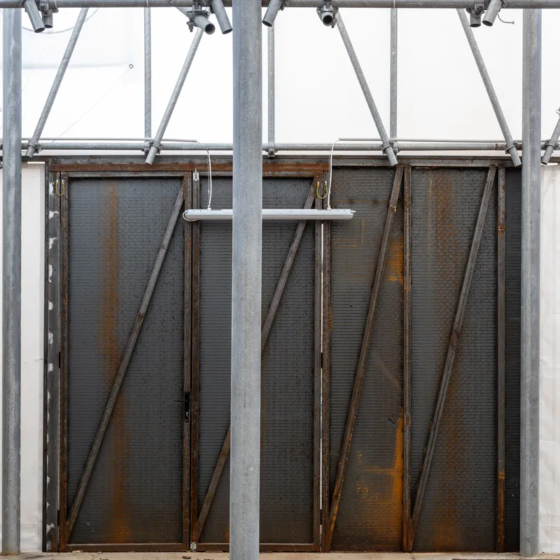 Weathered steel panel doors with diagonal bracing suspended beneath galvanized scaffolding structure