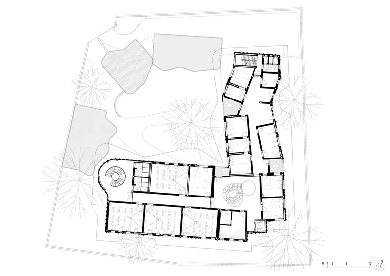 Site plan drawing showing an L-shaped building footprint surrounded by landscaping and trees