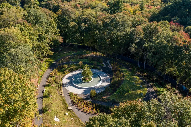 Overhead view of the circular plaza nestled within the wooded hillside with paths extending through trees