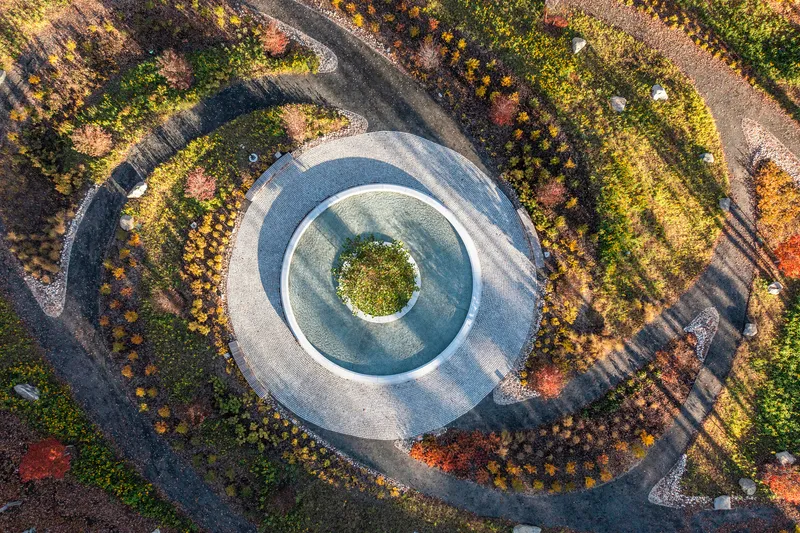 Aerial view of the circular water feature with central island and radiating landscape beds in fall