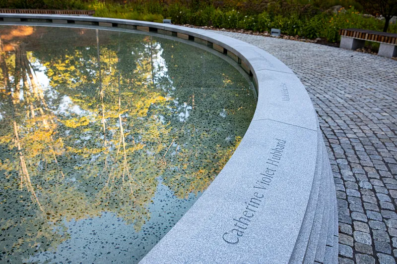 Detail of the carved granite fountain edge with inscribed text and cobblestone paving