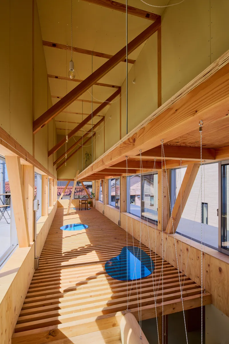 Upper level walkway with diagonal timber beams and slatted floor creating shadow patterns in afternoon light