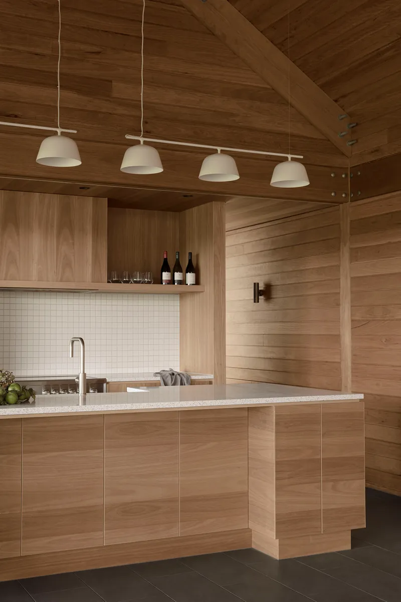Kitchen island with white tile backsplash and timber cabinetry under a vaulted plank ceiling