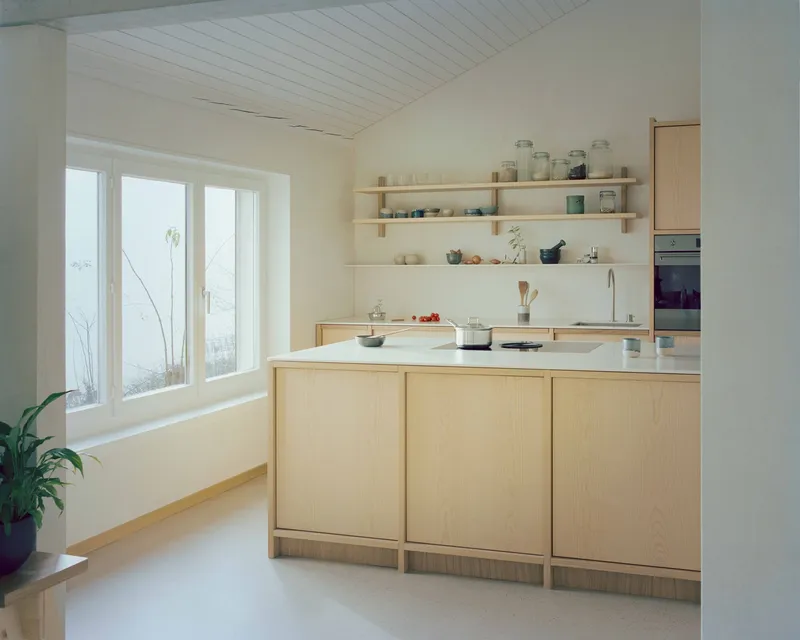 Kitchen island with light timber cabinetry and open shelving below white-paneled ceiling