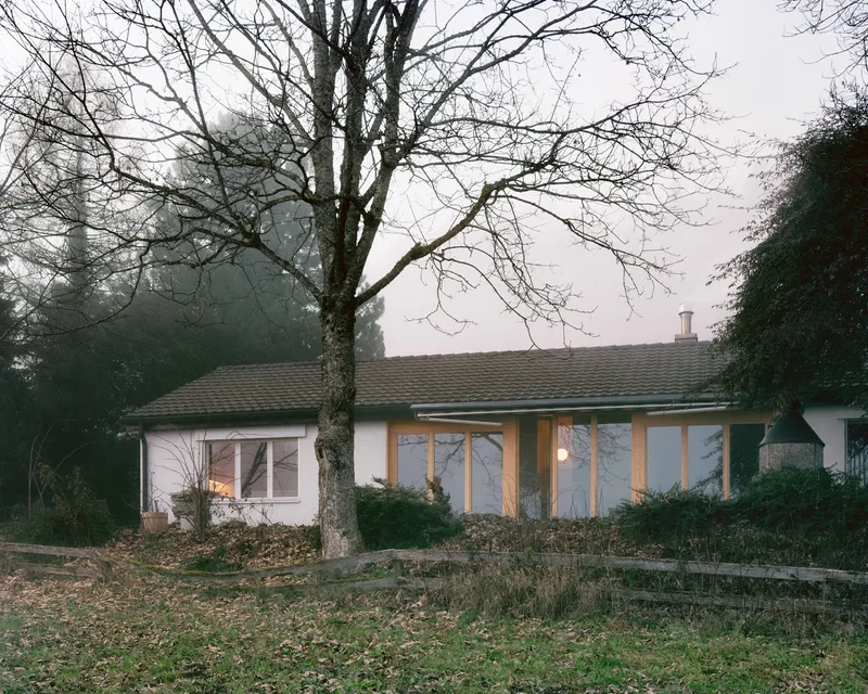 Garden facade with tiled roof and timber-framed windows beneath bare winter trees in mist