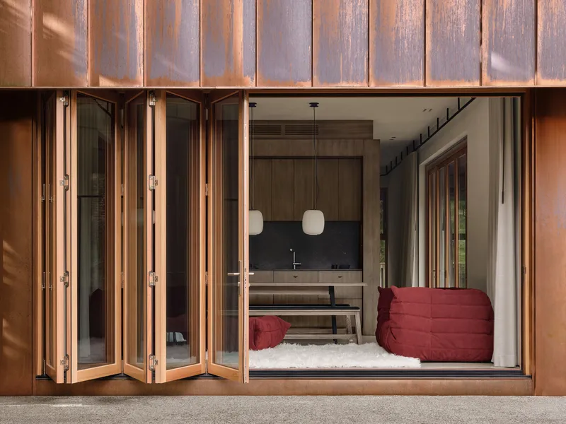 Open folding door threshold revealing interior with dark backsplash and red upholstered seating