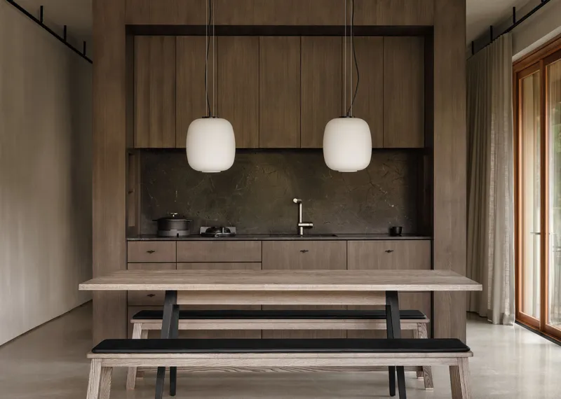Timber kitchenette wall with stone counter and twin pendant lights above bench seating