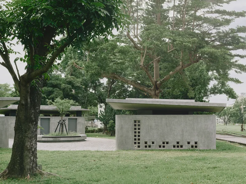 Side elevation showing concrete wall with gridded openings and thin roof slab in grassy clearing