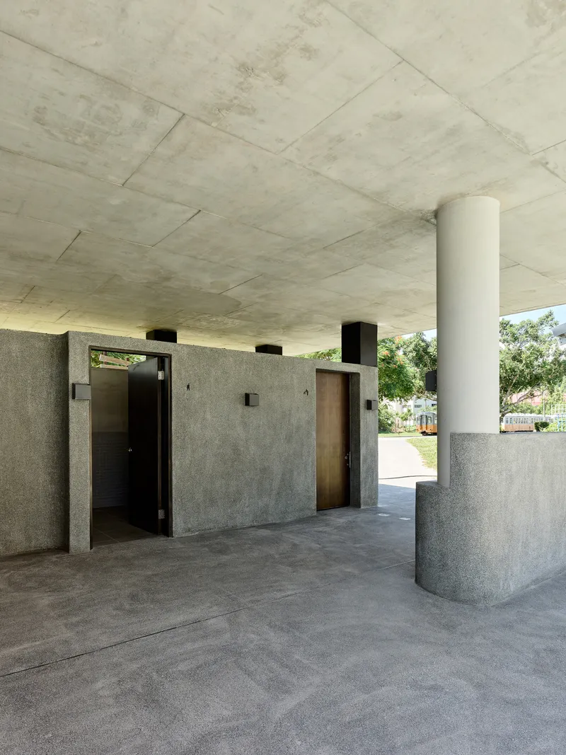 Covered porch area with board-formed concrete ceiling and cylindrical white column beside timber door