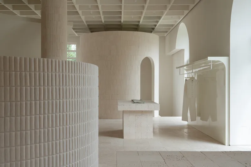 View through arched openings showing fluted cylindrical volume and stone display plinths under gridded ceiling