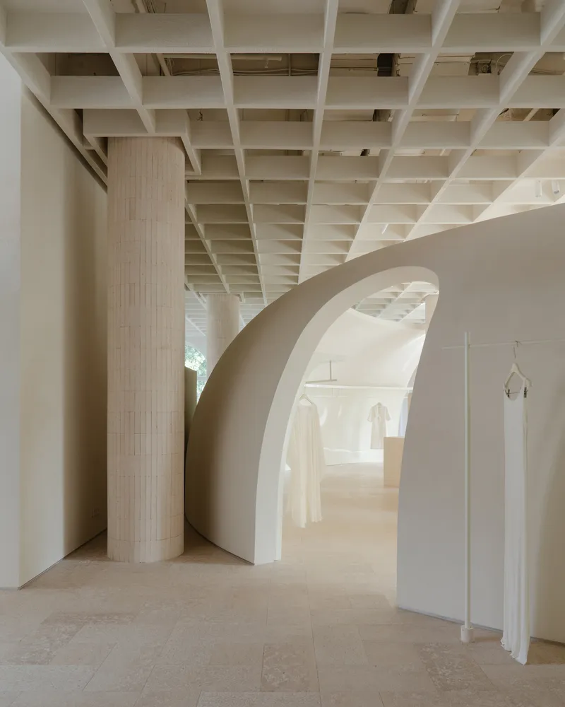 Curved archway framing fluted column and recessed display niches with hanging garments in daylight