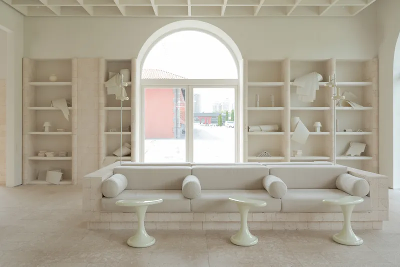 Built-in seating bench beneath arched window with shelving displaying ceramics and models