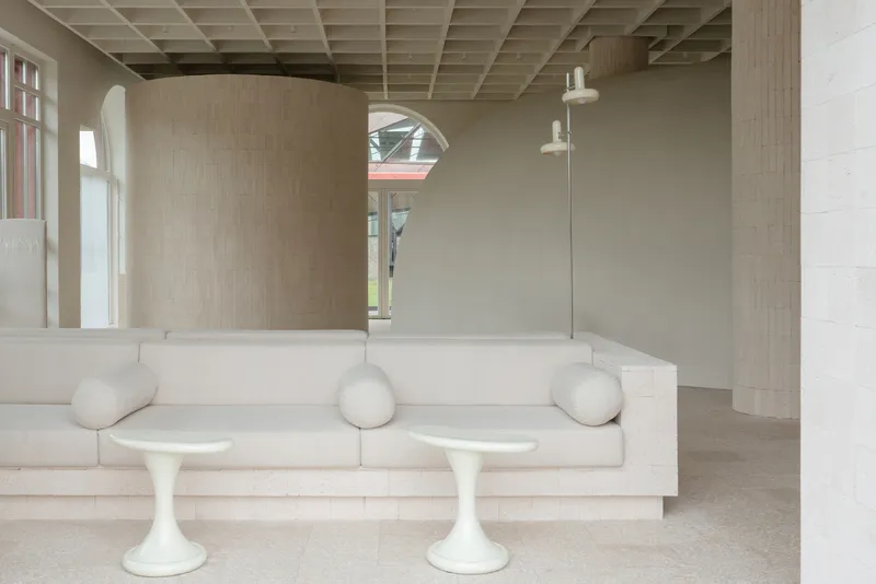 Curved timber-clad volume and built-in seating with rounded bolsters beneath exposed timber coffers