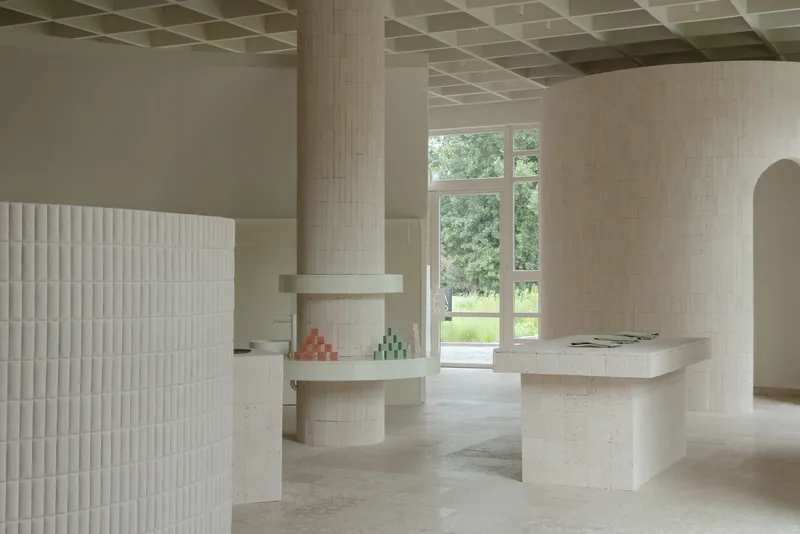 Interior with pale brick columns and coffered ceiling framing a view to the garden beyond