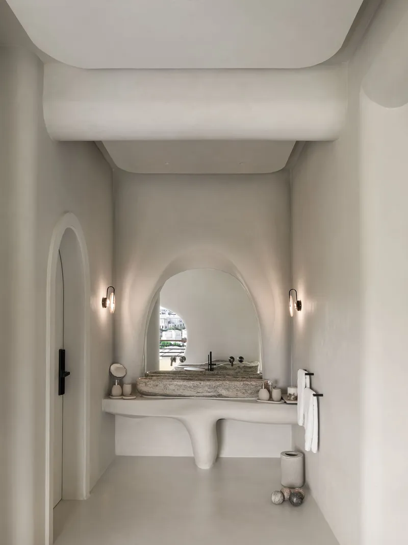 Powder room with arched vanity niche, stone basin and layered curved ceiling volumes