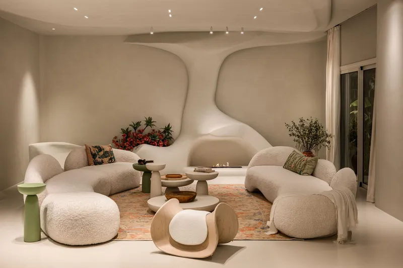 Living room with sculptural ceiling waves and curved seating around low tables under track lighting