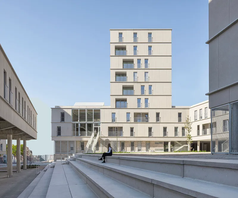 Precast concrete facade of the tower and podium seen across broad steps with a lone pedestrian