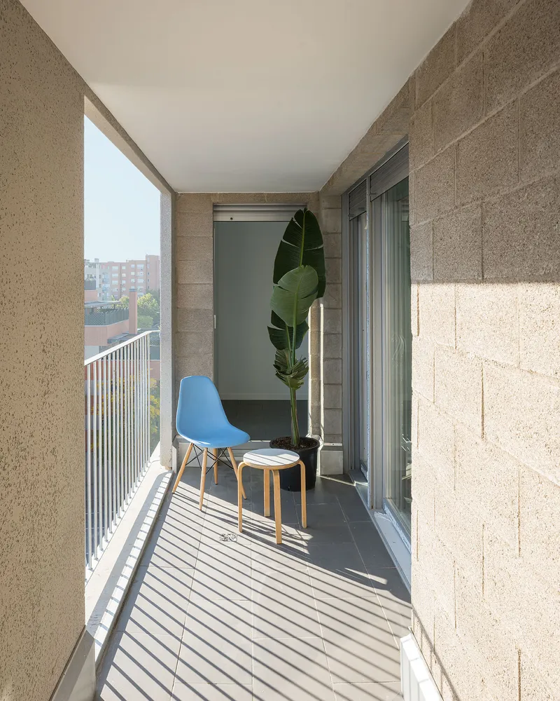 Narrow balcony with hempcrete block walls and vertical metal railings casting striped shadows