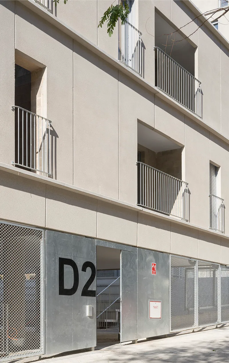 Ground-floor entrance with perforated metal screens and a metal door marked with building signage