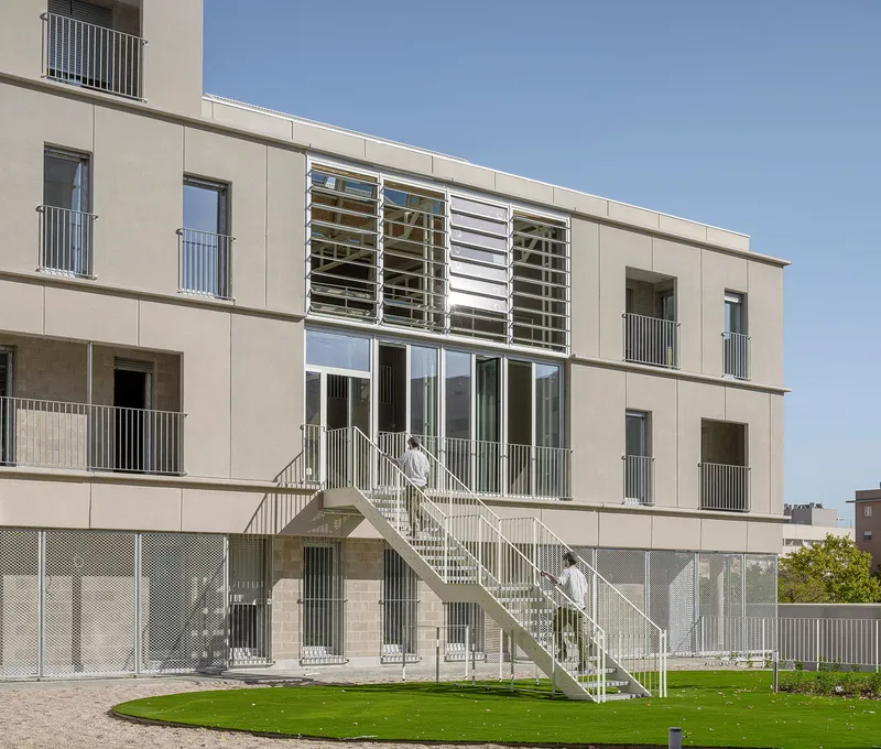 Rear facade with horizontal louvered sunshades above glazed doors and an external metal staircase
