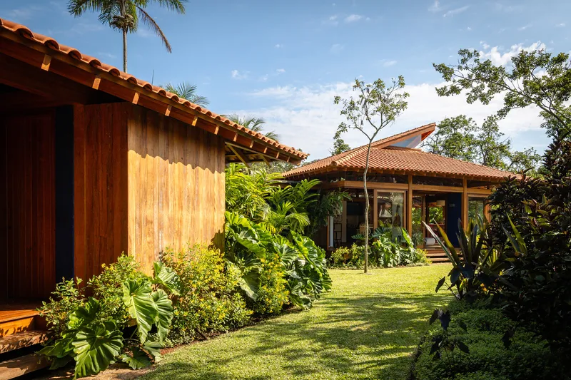 Vertical timber cladding and terracotta roof eave with tropical gardens between clustered pavilions