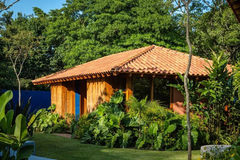 Timber pavilion with terra-cotta tile roof set among tropical landscaping and mature trees