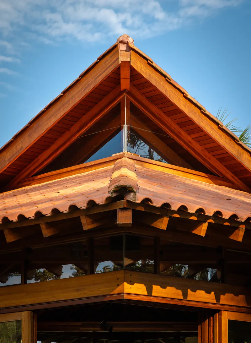 Layered gable peaks with exposed timber rafters and clay tile eaves against blue sky