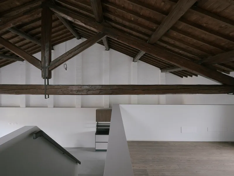 Upper level gallery with white walls and exposed timber beams and columns overhead