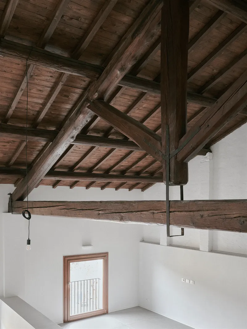 Mezzanine level with exposed timber roof structure and metal railing overlooking a lower room