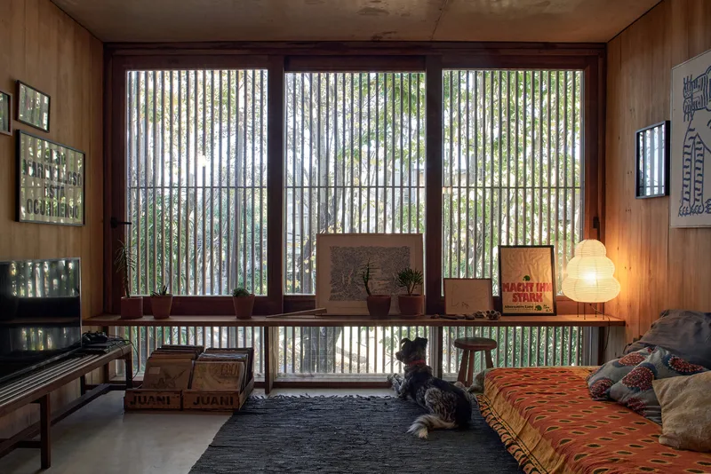 Wood-paneled room with vertical slatted screens filtering daylight and two children seated on the floor