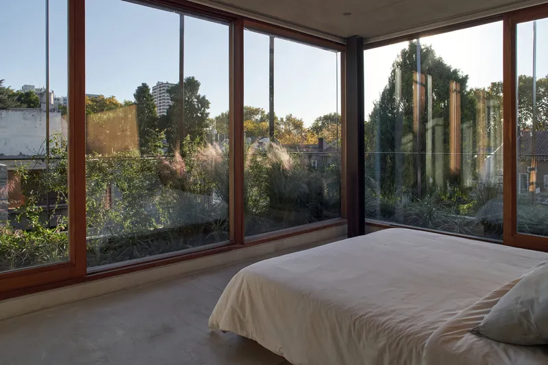 Corner glazing with timber frames opening onto a planted terrace at dusk