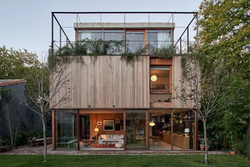 Garden facade with timber slatted upper volume, glazed ground floor opening to lawn and rooftop steel frame