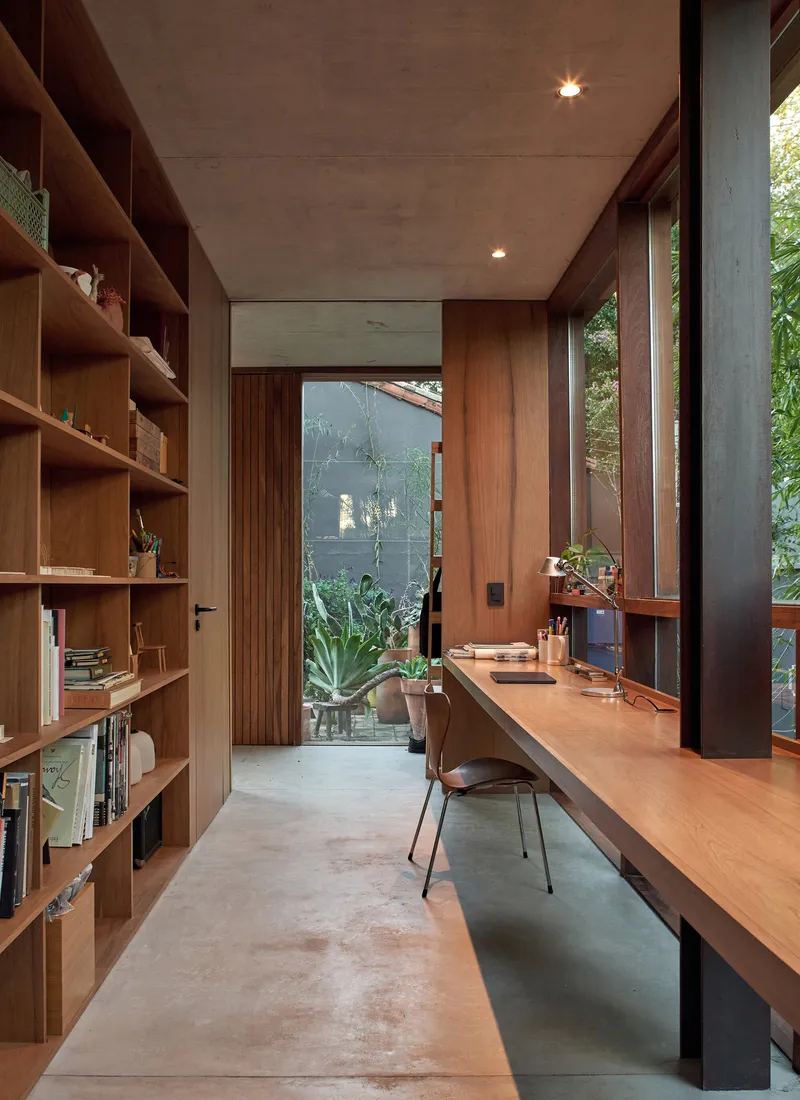 Study with built-in timber desk, shelving and concrete ceiling illuminated by recessed lights