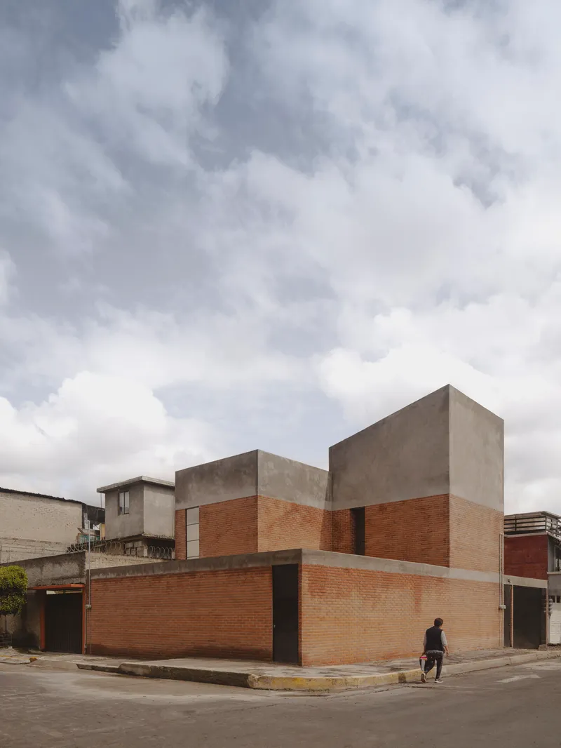 Corner view of the brick and concrete facade under an overcast sky with a pedestrian