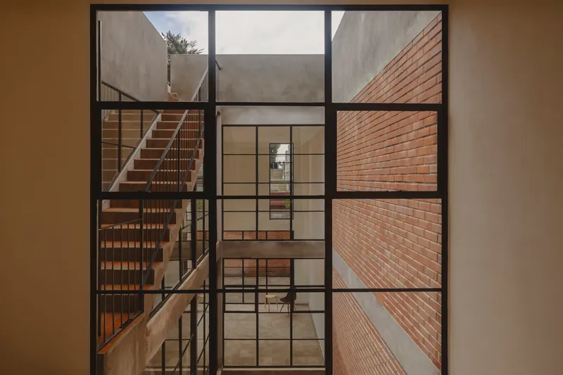Black steel window framing views into the interior courtyard and timber staircase beyond
