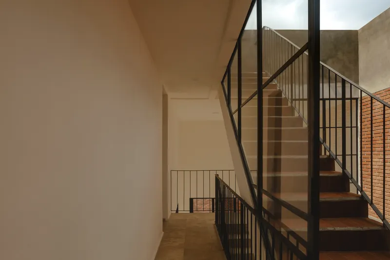 Interior view of concrete stairs with black metal railings and glass panels in soft daylight