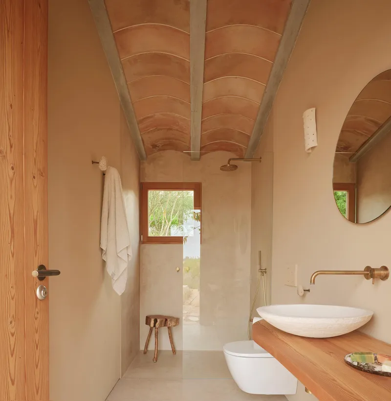 Bathroom with vaulted timber ceiling and arched opening leading to a walk-in shower with garden view