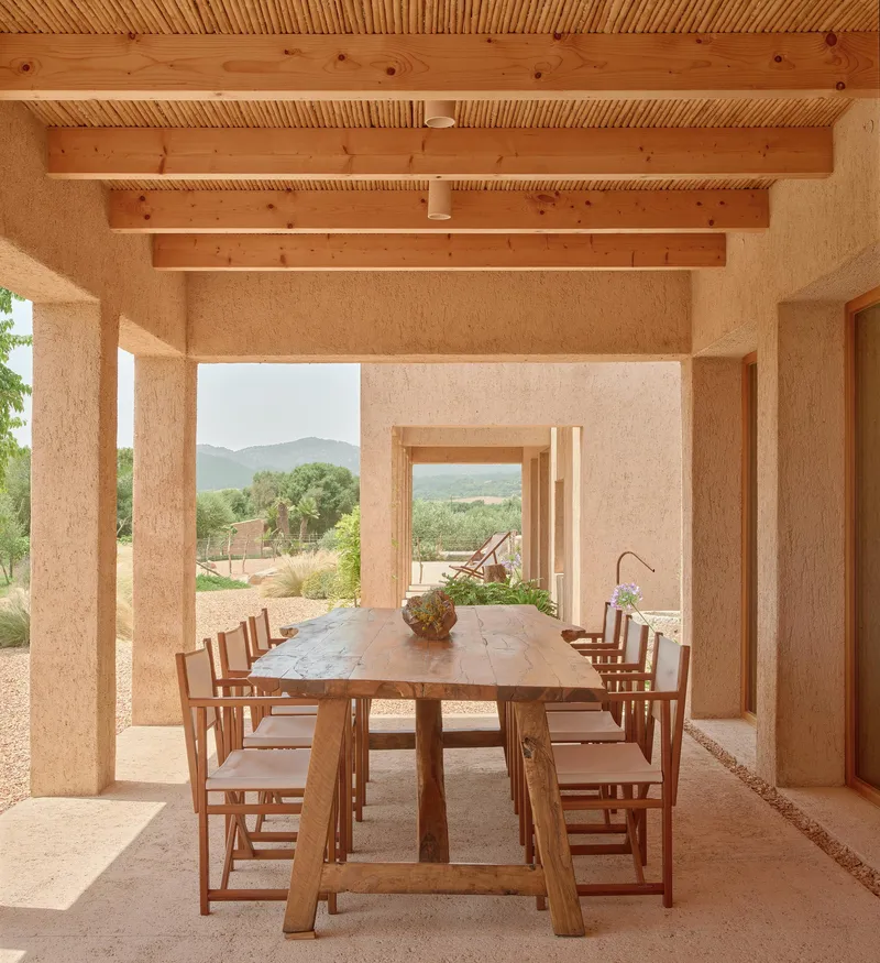 Covered dining terrace with exposed timber beams and ceiling looking toward mountains and landscape through openings