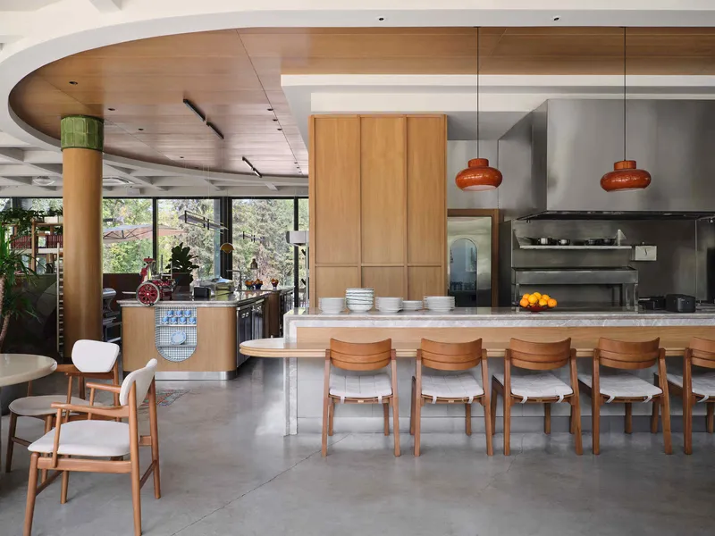 Kitchen bar with marble counter, timber stools, and circular wood ceiling soffit beside full-height windows