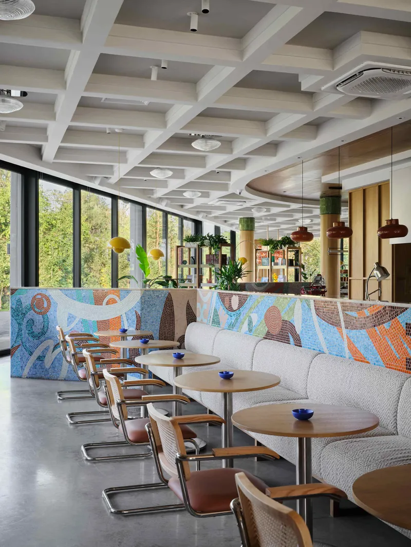 Banquette seating along mosaic tile wall with coffered ceiling and glazed curtain wall beyond