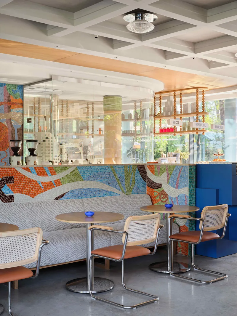 Booth seating with mosaic tile backdrop and glass partition reflecting suspended wooden shelves