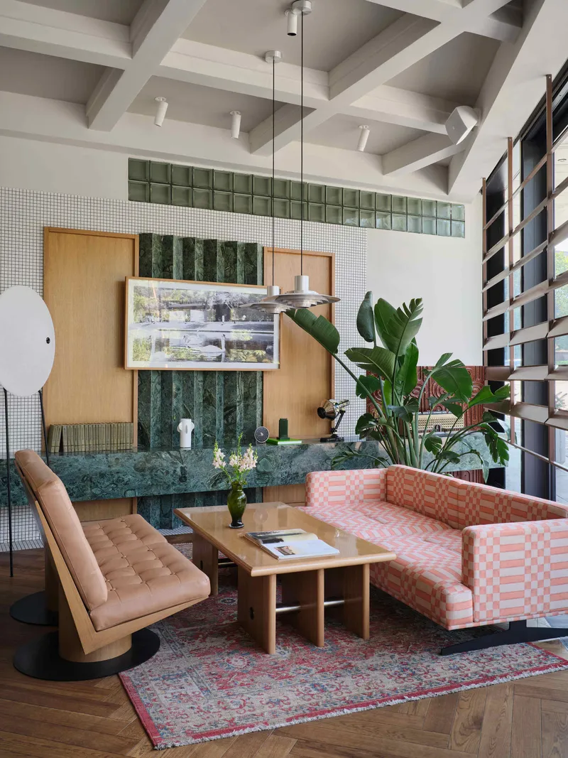 Lounge seating around green marble table with mosaic wall and timber cabinetry behind