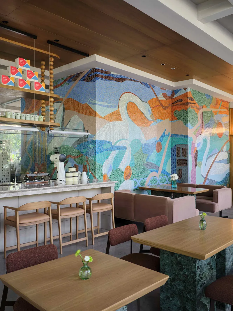 Cafe counter with mosaic mural of swans and landscape, timber seating and coffered ceiling detail