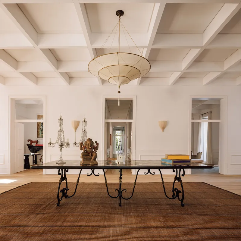 Dining room with coffered ceiling and tiered pendant fixture above a marble table with iron legs