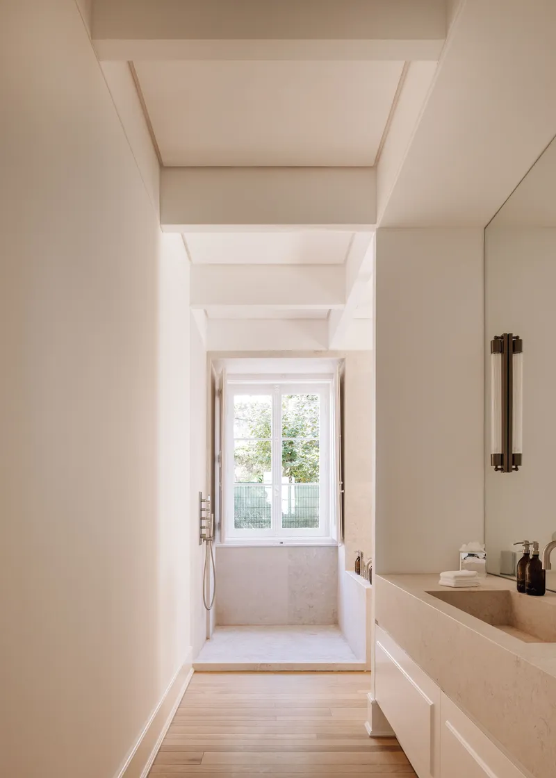 Bathroom corridor with coffered ceiling and stone vanity leading to a windowed shower area